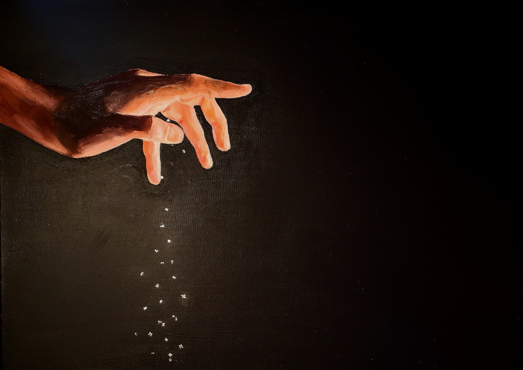 A brightly lit open hand on a dark background. There a small letters falling from the hand.